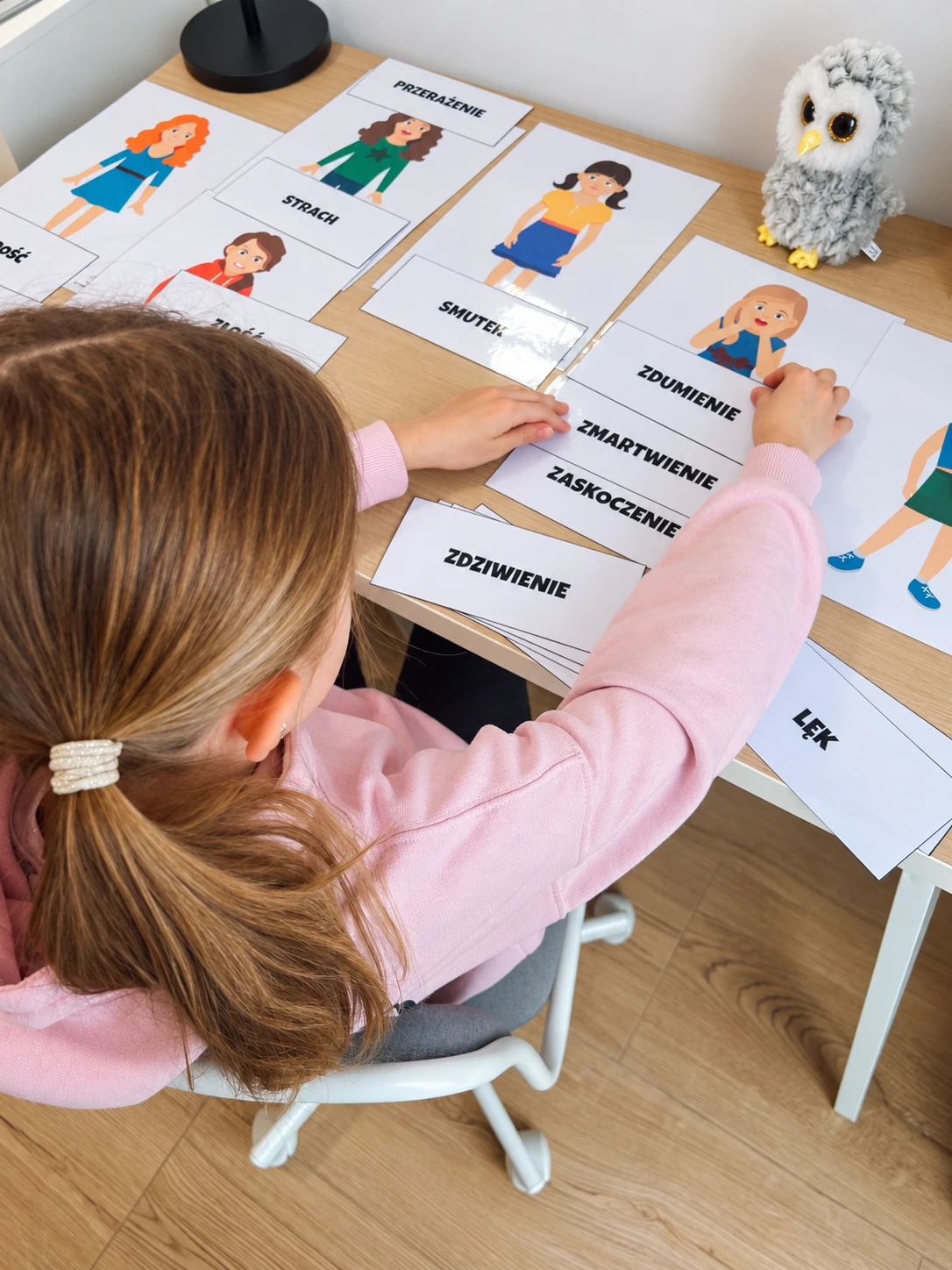 Dziecko pracuje z kartami emocji podczas zajęć logopedycznych